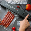 Mano presionando el botón de la selladora con longanizas selladas al vacío